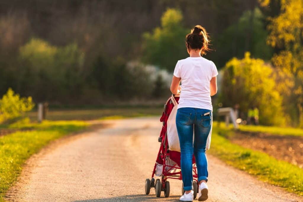 Mom pushing baby stroller down a long lane.