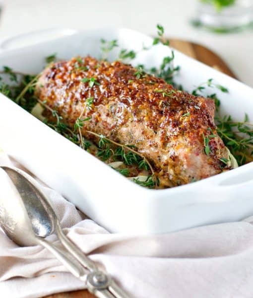 Seasoned pork tenderloin in ceramic baking pan.