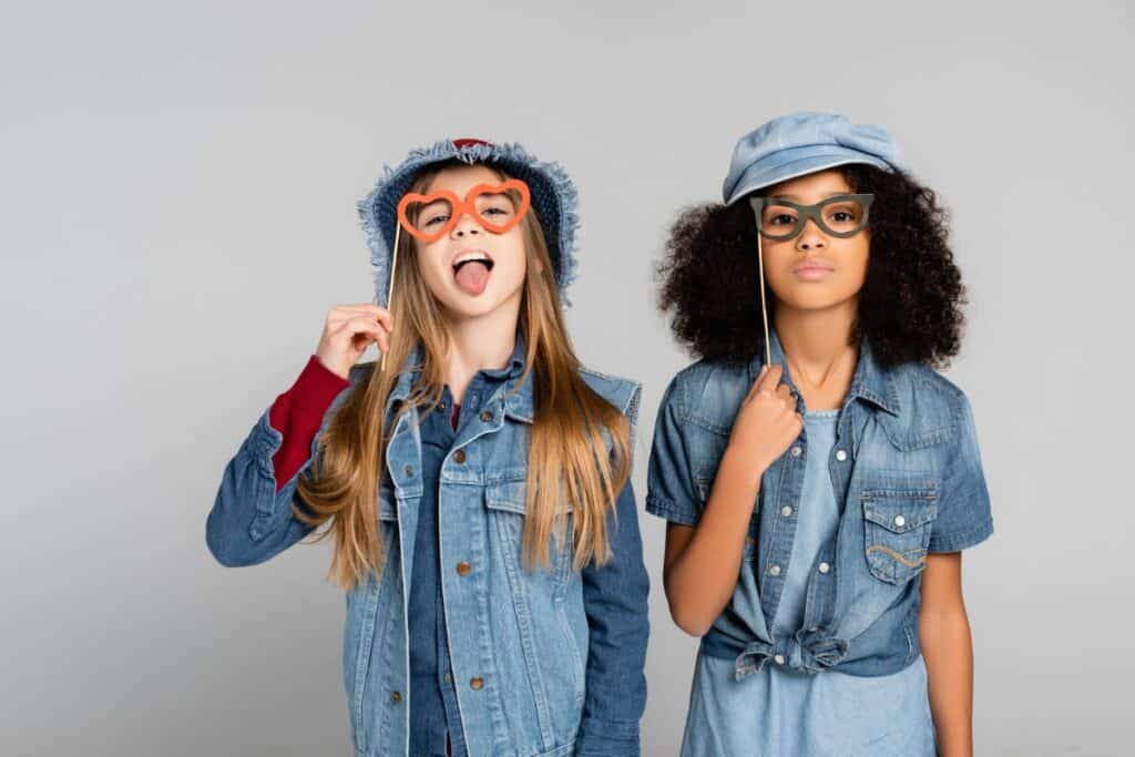 Tween girls holding up silly heart glasses, posing for photo