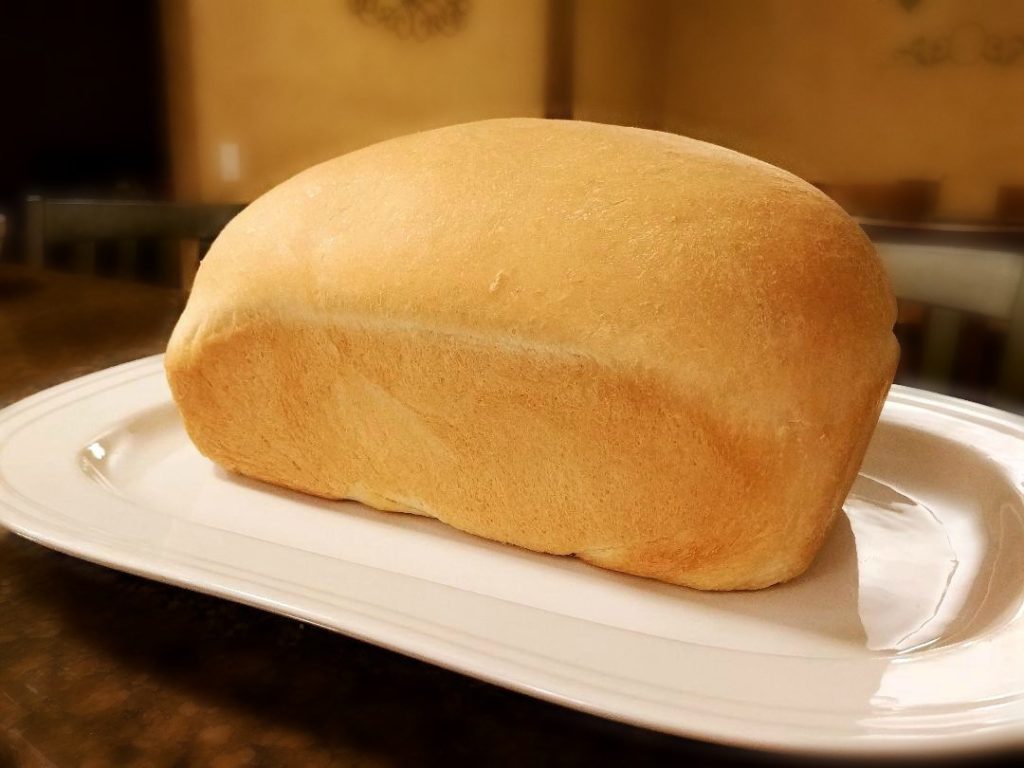 Feature image for Thrifty Homemade Sandwich Bread Recipe- the completed baked loaf on a serving platter.