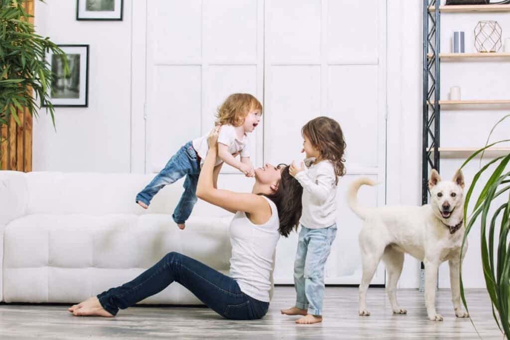 Mom playing with kids and puppy in living room.