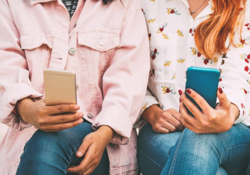 Transcriptionist course should include networking: Image of women sitting side by side holding smart phones.