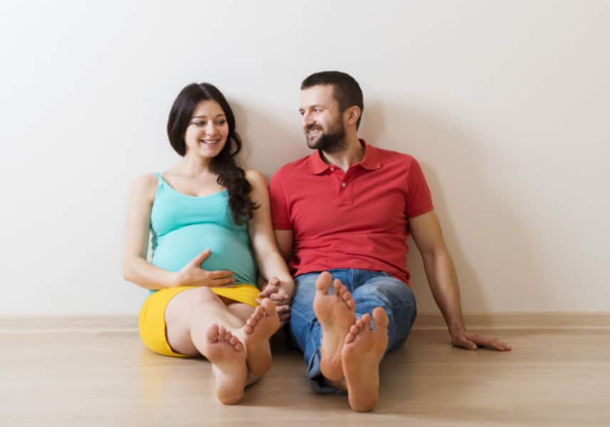 New parents preparing for newborn - sitting on the floor together daydreaming.