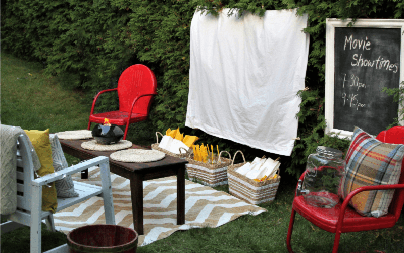 Summer activities for kids: outdoor movie night set up in the backyard with rug, chairs and baskets of goodies.