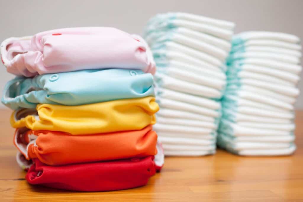 stack of cloth diapers next to a stack of disposable diapers.