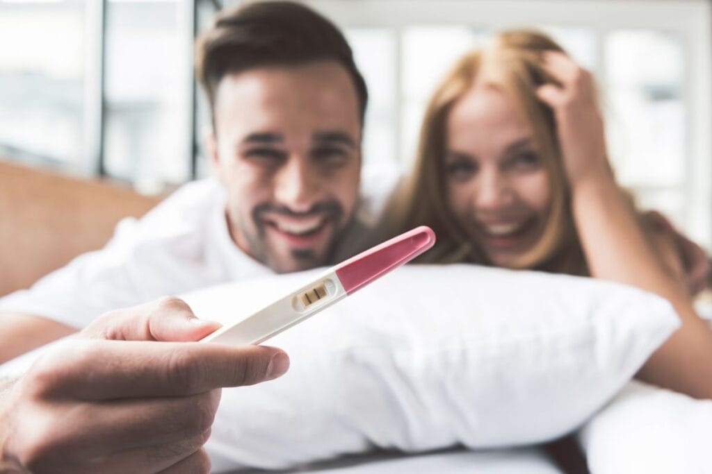 Couple holding positive pregnancy test. What to do when you're pregnant.