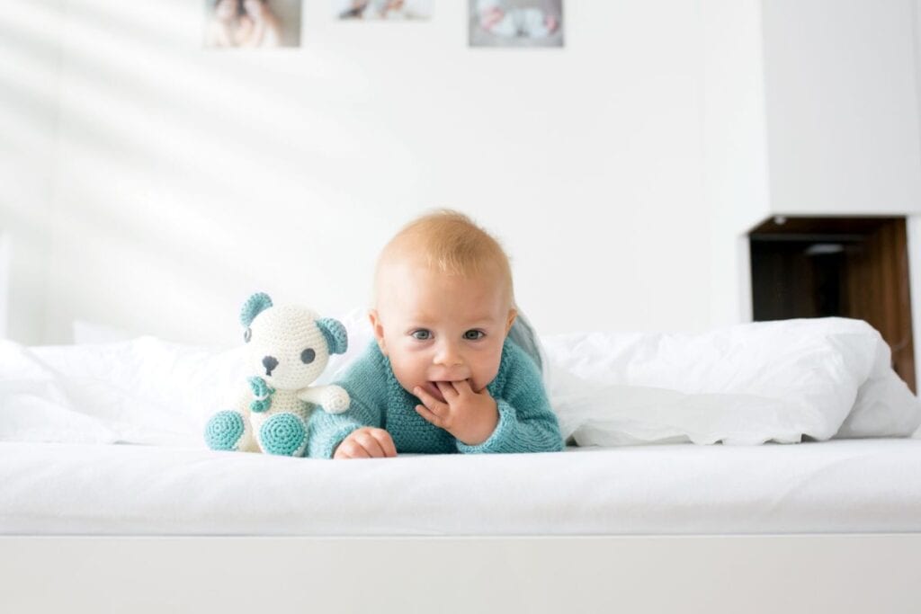 Happy baby lying on bed in blue outfit