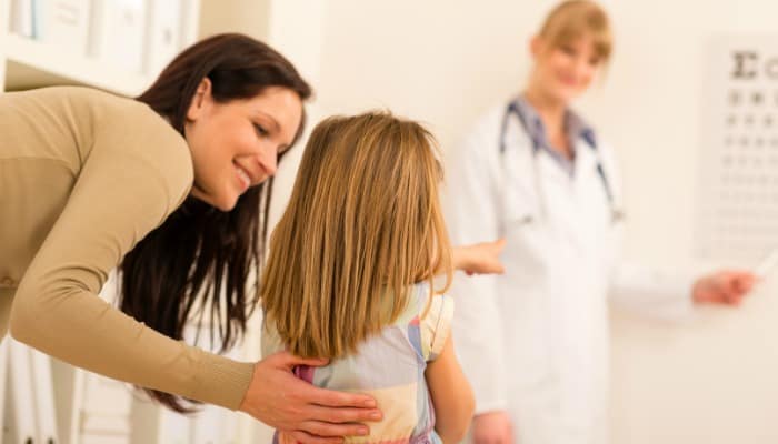 Teaching Respect article: respecting other adults in doctor's office. A mom encourages her young daughter, has arm around her little girl.