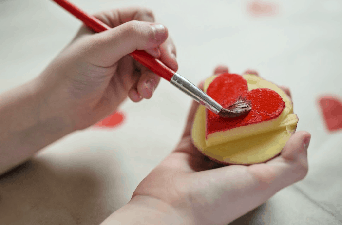 Image of child painting a potato stamp. Concept of idea for Indoor activities for kids- potato stamping.