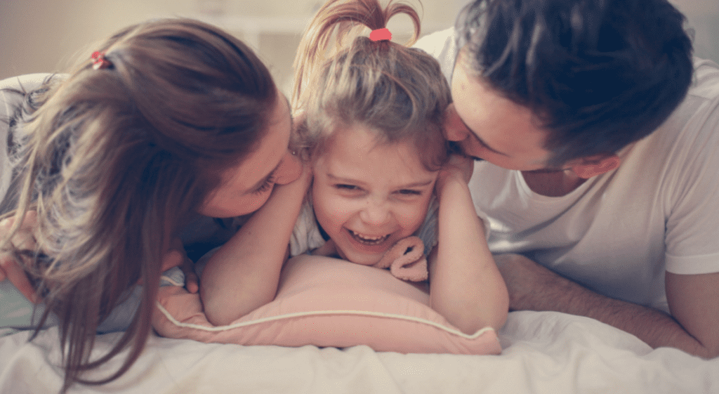 mom and dad with toddler daughter laughing together