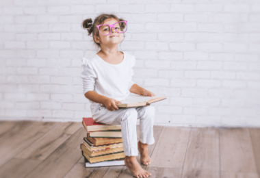 How to raise a responsible child instead of entitled one: featured image for this article- child sitting on a stack of books. Link below to article.