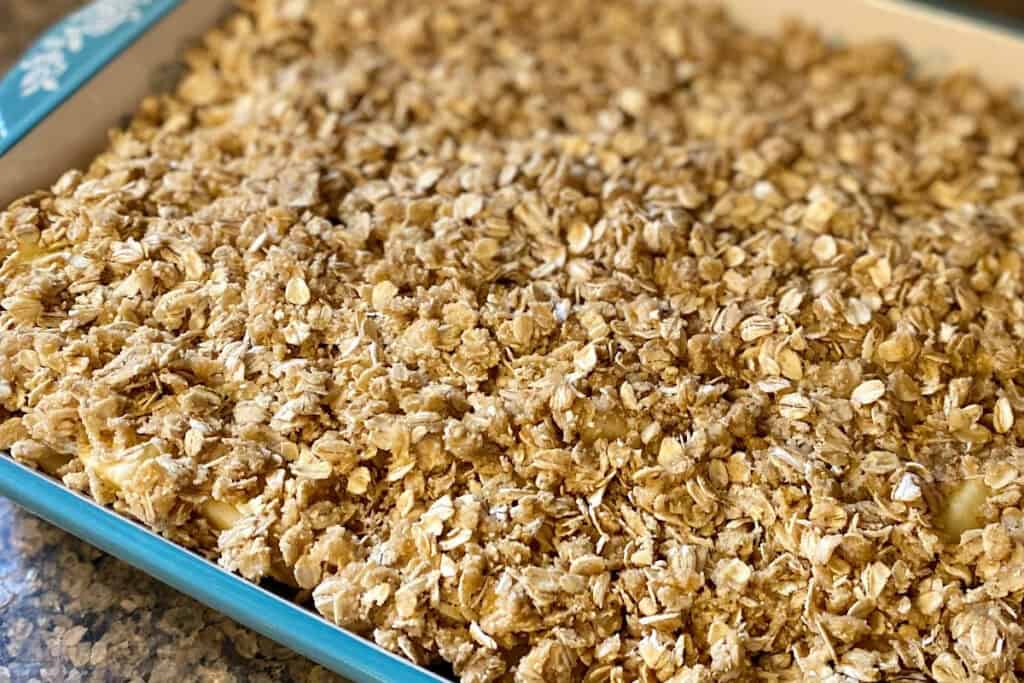 Finished apple crisp in teal colored stoneware baking dish, up close.