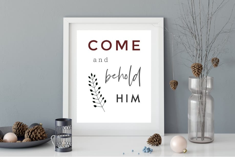 Framed Come and Behold Him printable Christmas sign on a decorated tabletop.