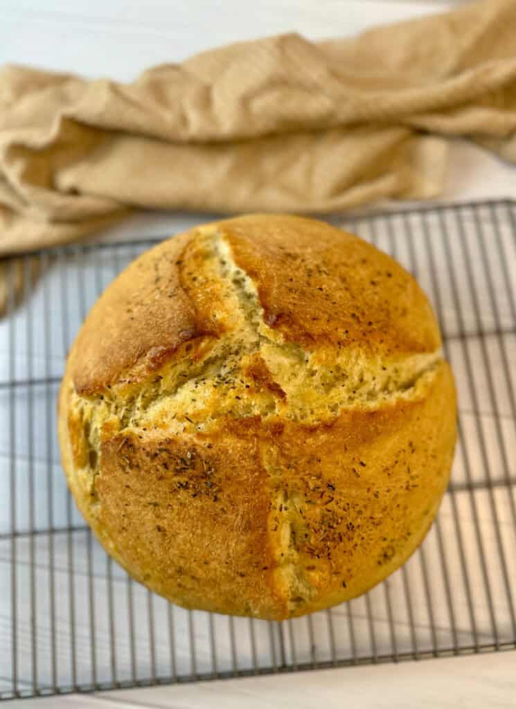 No knead Dutch oven bread loaf on cooling rack.