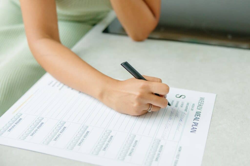 Woman writing a weekly meal plan.