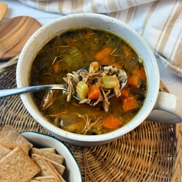 Healthy turkey soup on a soup bowl on a rattan tray.