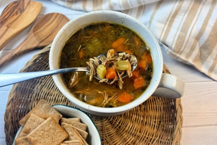 Healthy turkey soup on a soup bowl on a rattan tray.