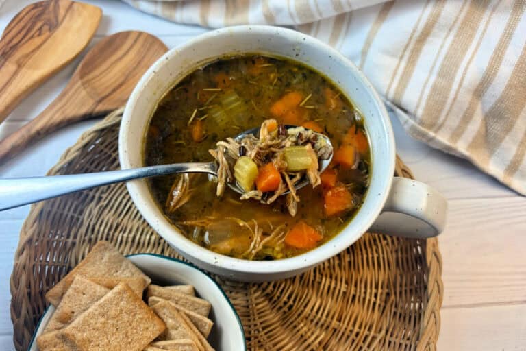 Healthy turkey soup on a soup bowl on a rattan tray.