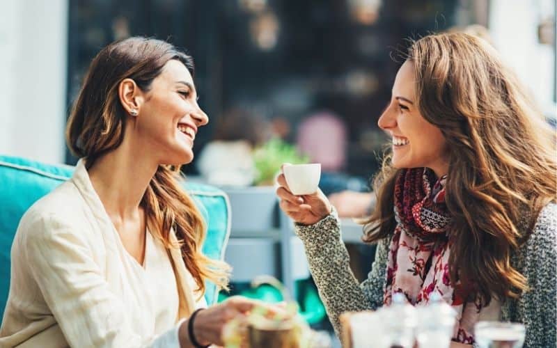 Two women chatting and smiling over coffee.