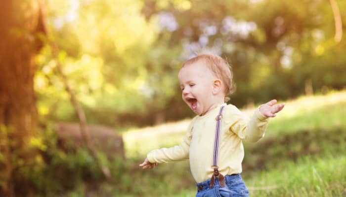 Toddler boy running through a field: concept of why potty training boys is HARD