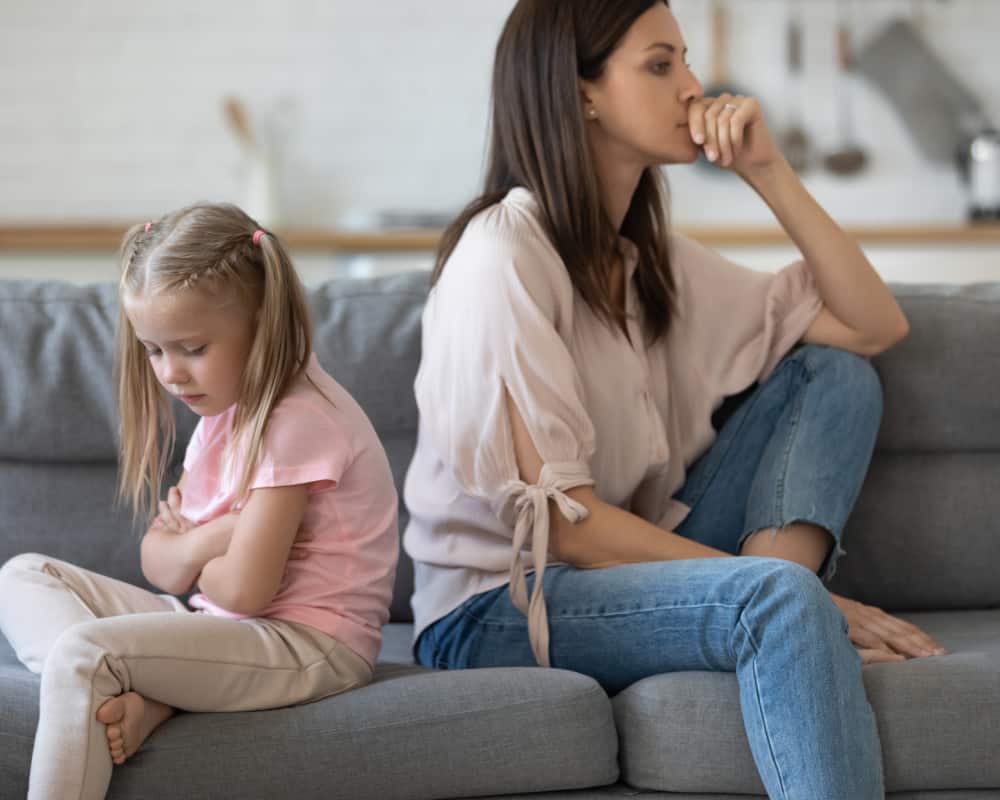 Mom and daughter sitting back to back on a couch; concept of walking away or taking a break from talking back behavior