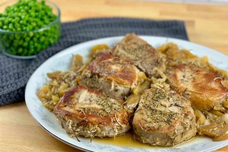 Pork chops, onions and apples on a serving platter.