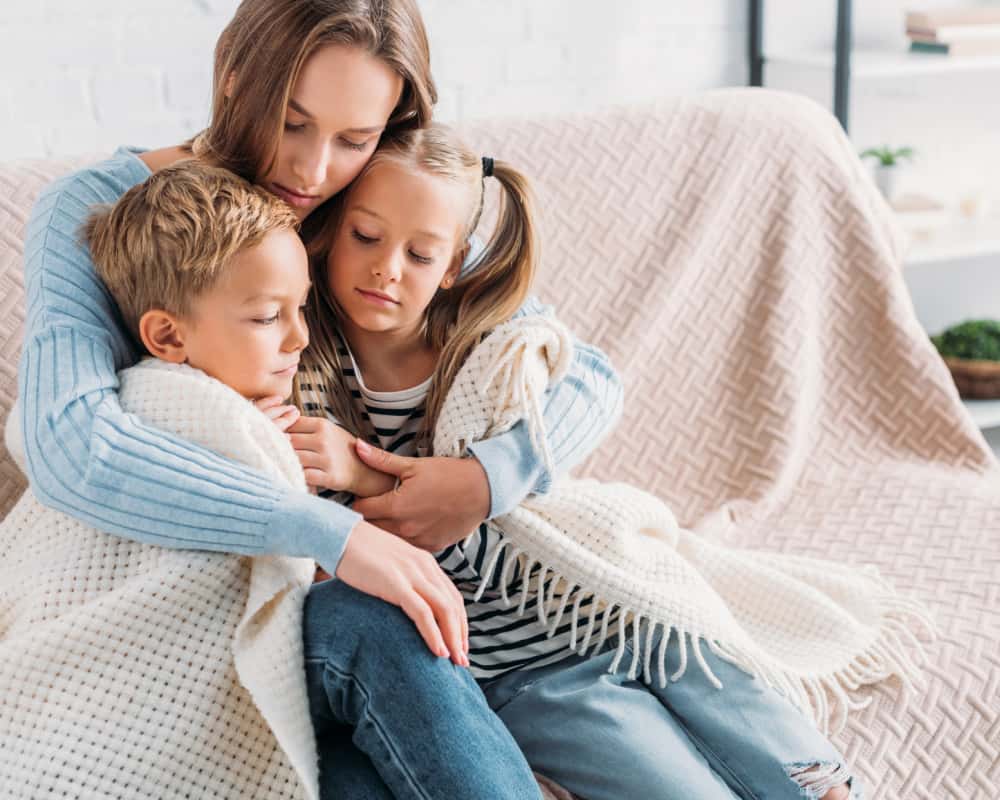 Image of a mom and kids cuddled up on the couch, with mom looking protective. Concept of meditating on Scripture for anxious thoughts as a mom