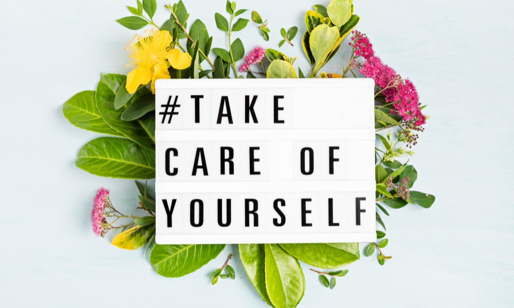Letterboard on a floral background that reads "#take care of yourself"