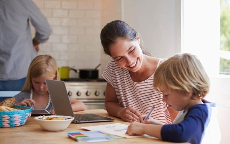 Mom helping young children with school work: concept of Making kids responsible for their own homework