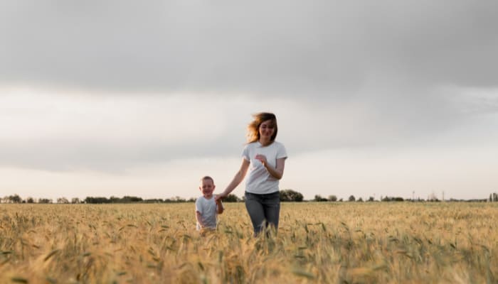 teaching kids to respect parents and adults: a young mom runs in a field with her son, spending quality time together.