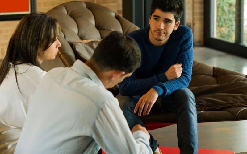 teen learning consequences and responsibility- talking to parents in living room.