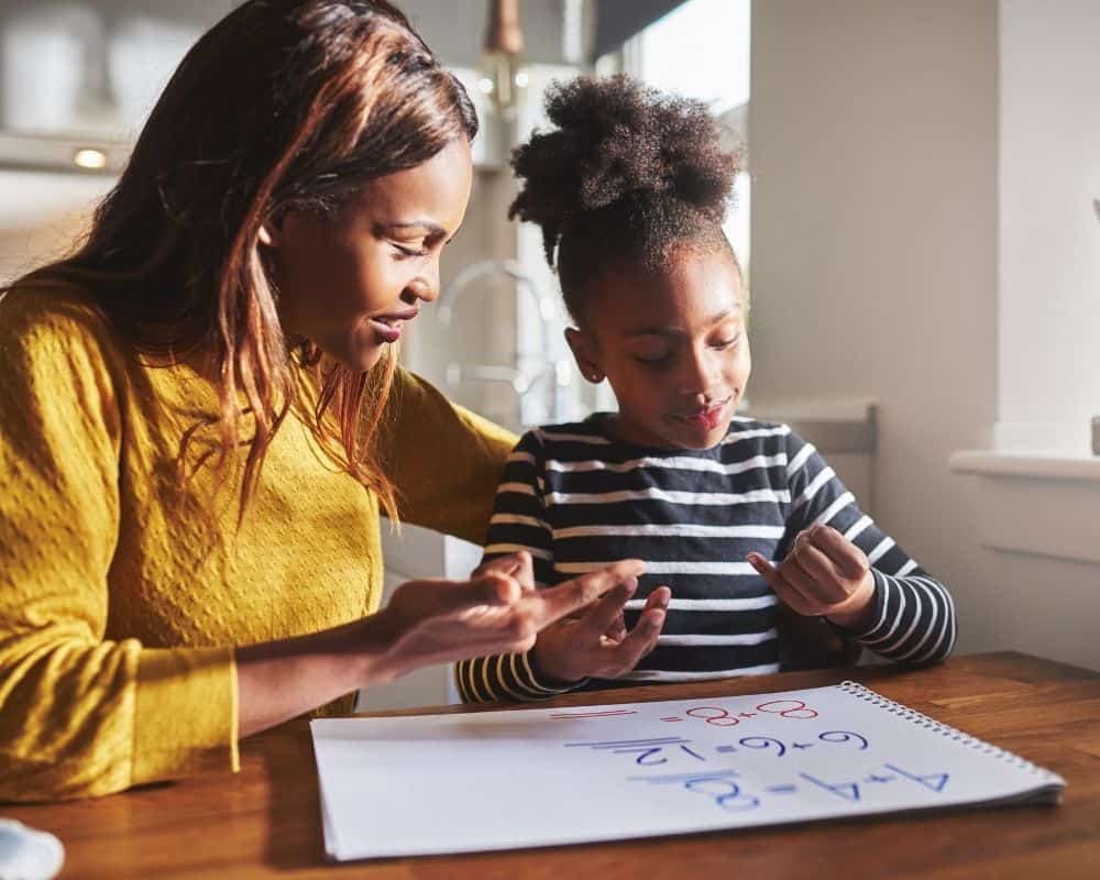 An African-american mom workong on math with her preteen daughter. Prayer for students at home with parents.