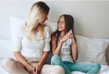 Image of mom talking to teenage daughter, sitting on a bed. Links to article below: Handling tween emotions.