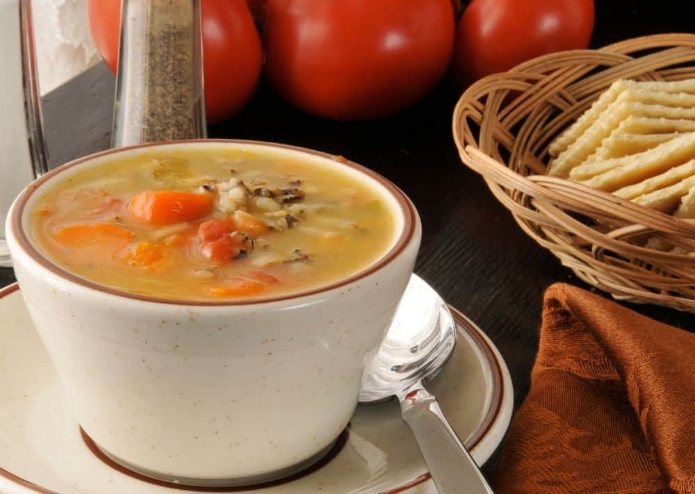 Chicken or turkey and rice soup in a bowl with crackers on the side.