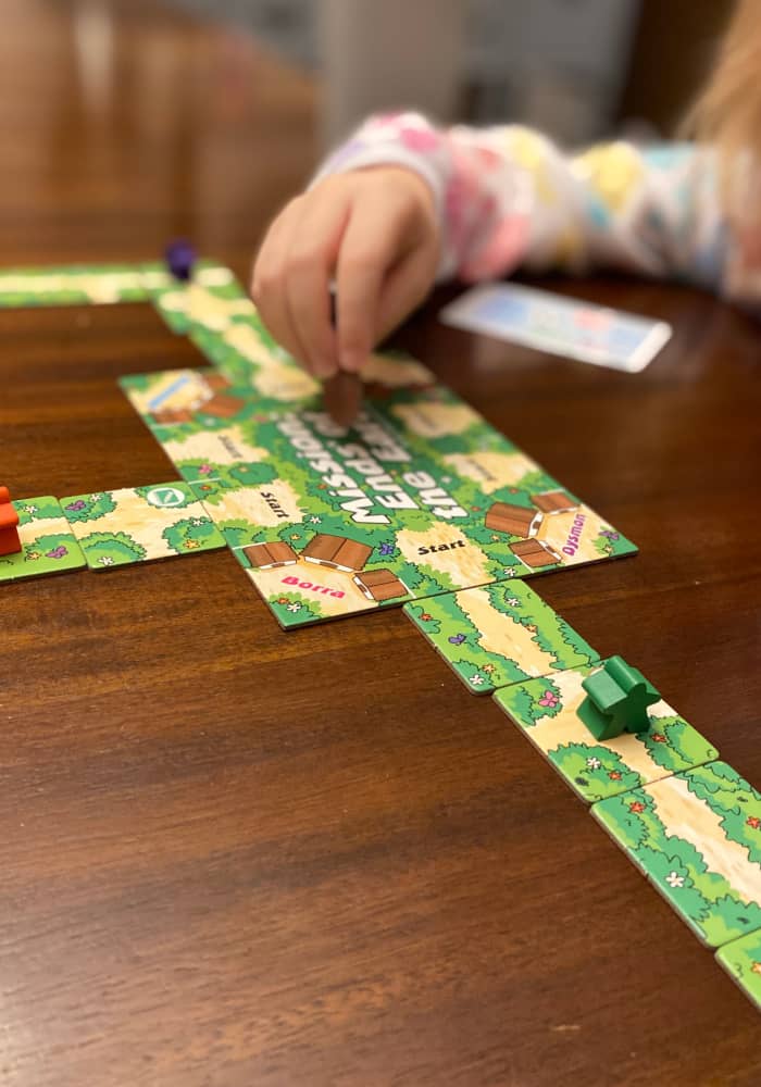 Image of child playing a Bible board game and holding a game piece.