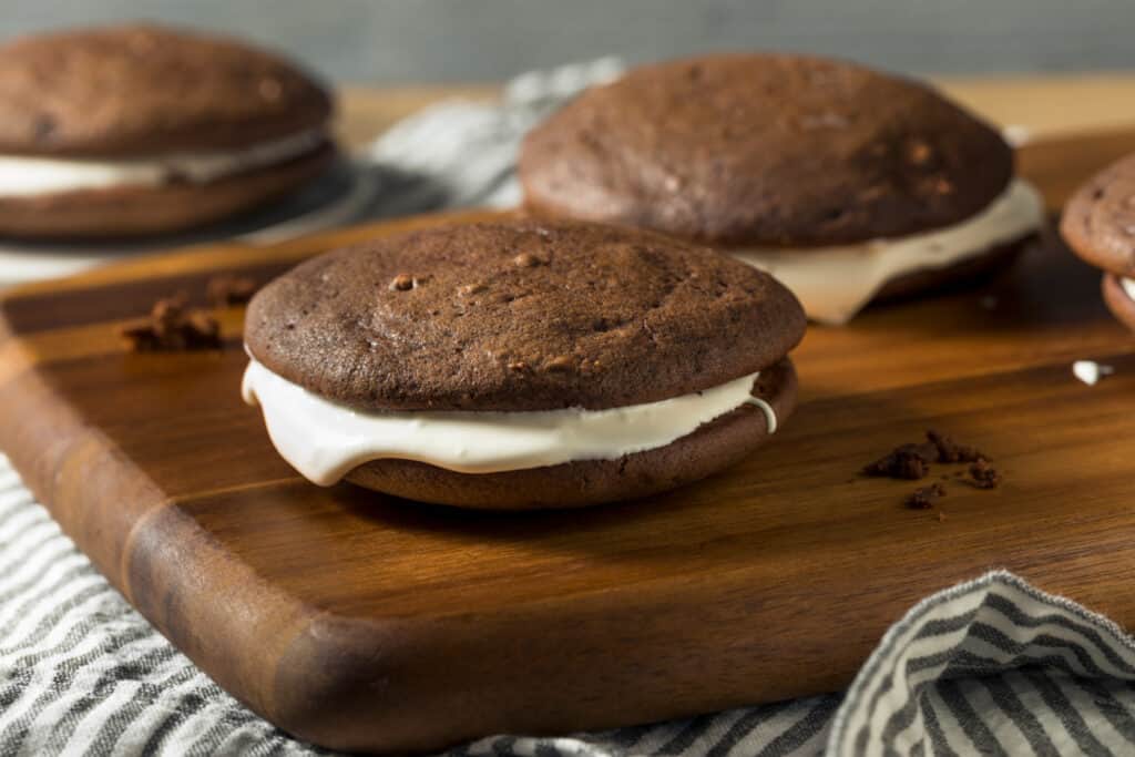 Chocolate cream pies on a wooden cutting board.