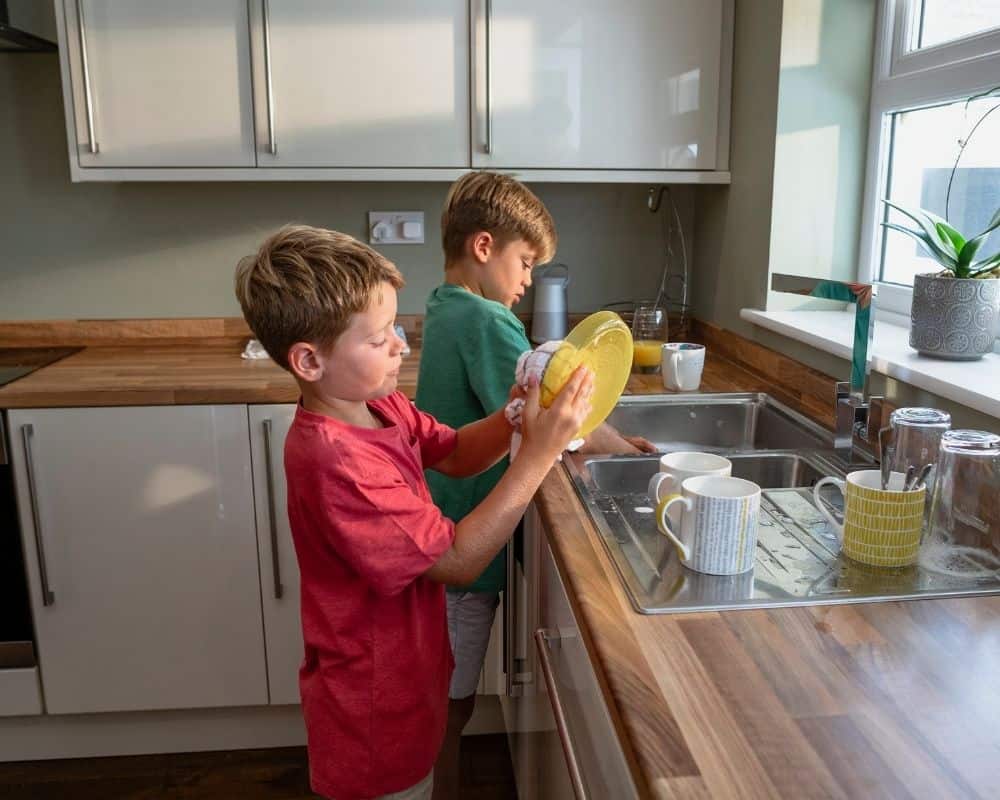 Two preteen boys doing dishes by hand. Concept of appropriate discipline for back talk.