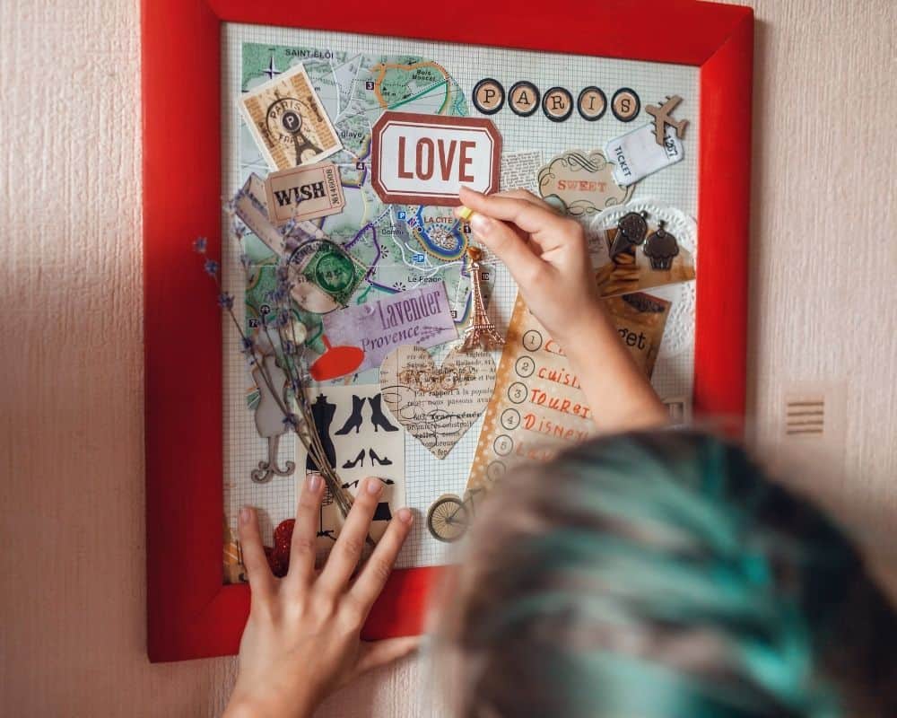 Image of teen girl finishing a collage of her favorite place (Paris) and hanging it on her bedroom wall.