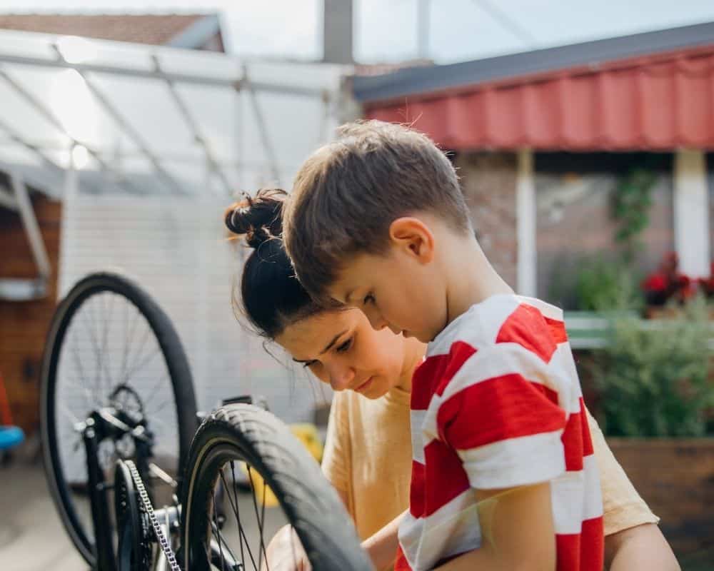 Mom helping her young son fix his bicycle. Concept of building relationship and reinforcing Bible teachings during day to day conversations.