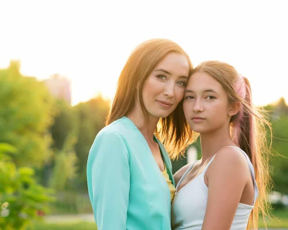 Mom standing with teen daughter, heads touching, concept of calm relationship.