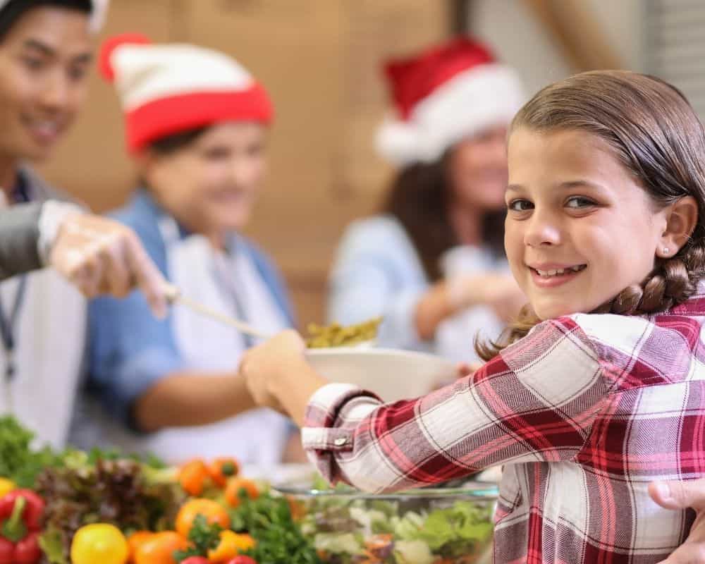 Image of girl receiving a plate of food at a community Christmas meal.