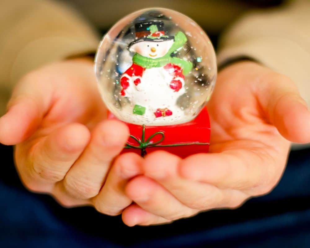 Image of snowman snowglobe held in the hands of a small child. Concept of DIY snowglobe activity.