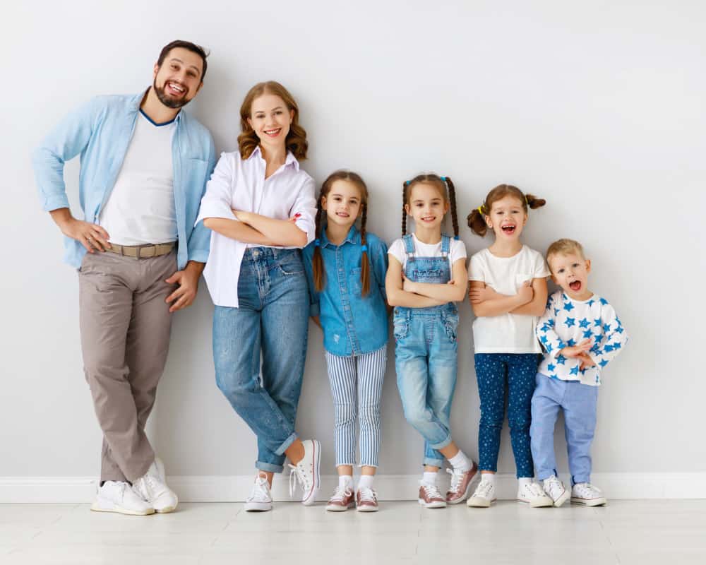 Mom and dad and four kids standing in a row against a white background. Concept of happy large family.