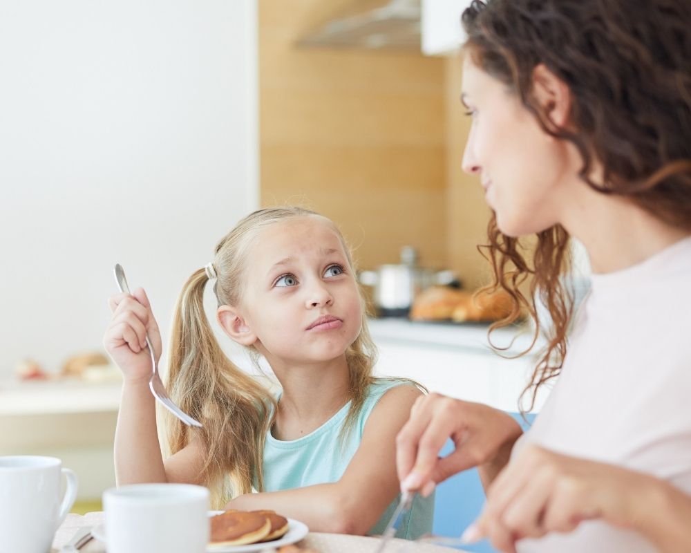 Mom and daughter eating breakfast while mom explains chores and her expectations.