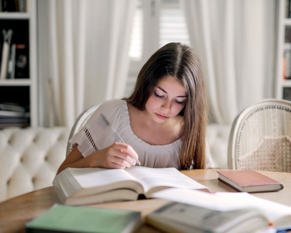 Teen doing homework at the kitchen table.