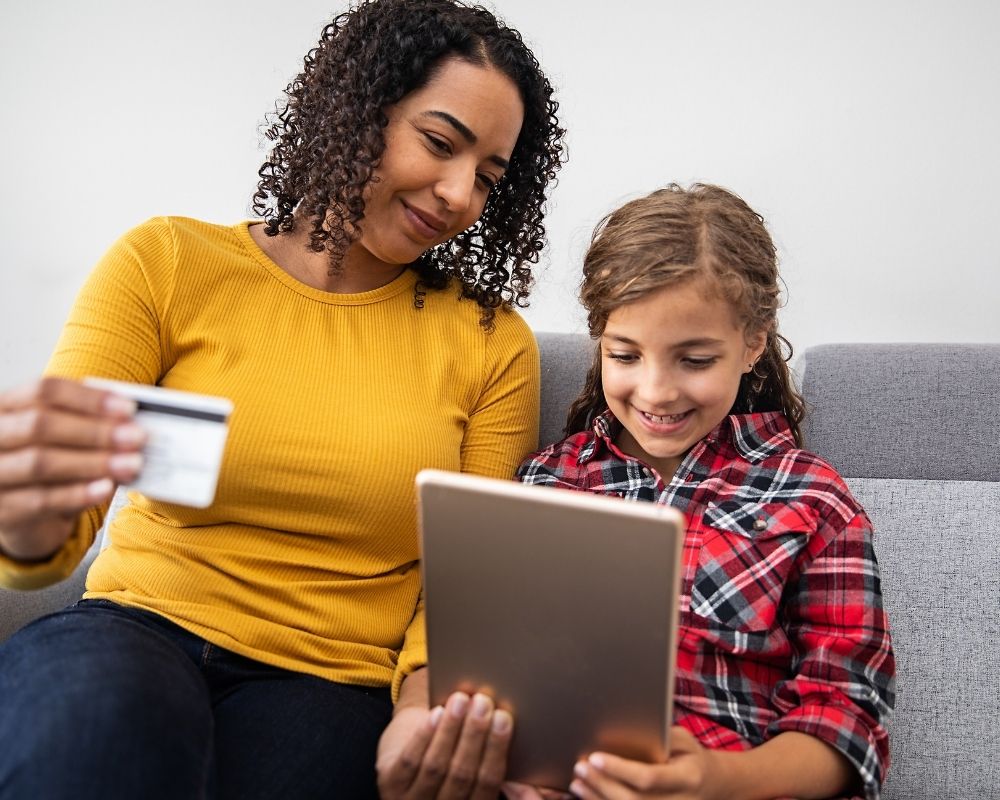 Mom and daughter shopping online using daughter's card- concept of spending an allowance.