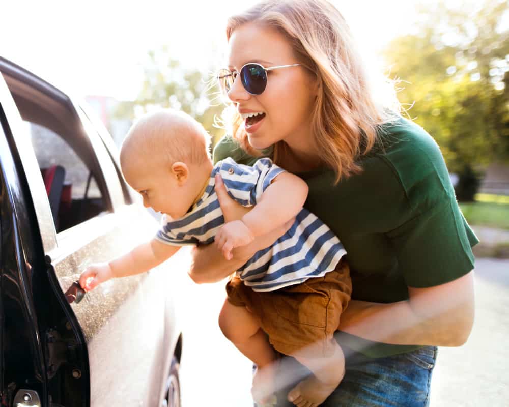 Mom getting baby into car- concept of the hassle of getting four kids ready to go in the morning!
