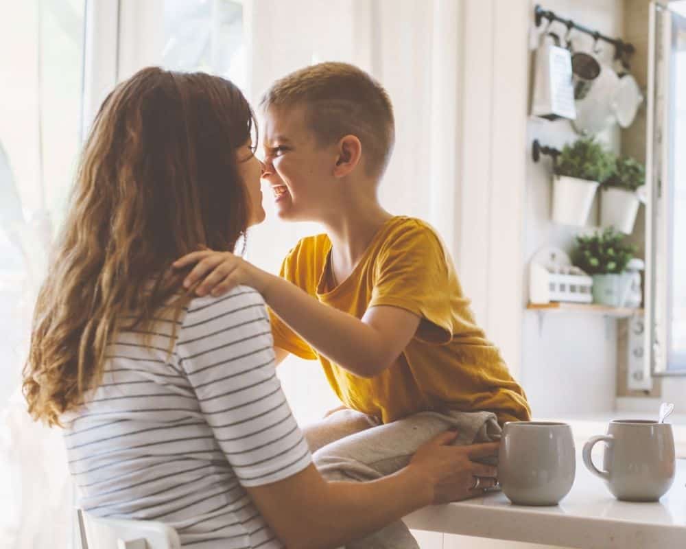 Image of mom and young son sitting on kitchen counter, nose-to-nose. Concept of stages of motherhood.