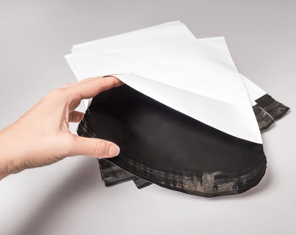 Image of woman's hand opening a poly mailer bag to demonstrate how they are used to ship items sold on Marketplace.