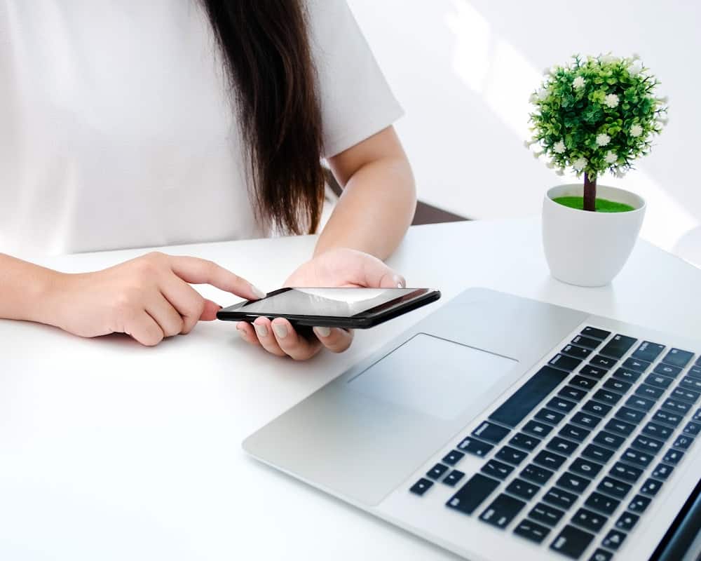 Image of woman holding calculator and sitting in front of a laptop at a desk- concept of pricing items to sell online.